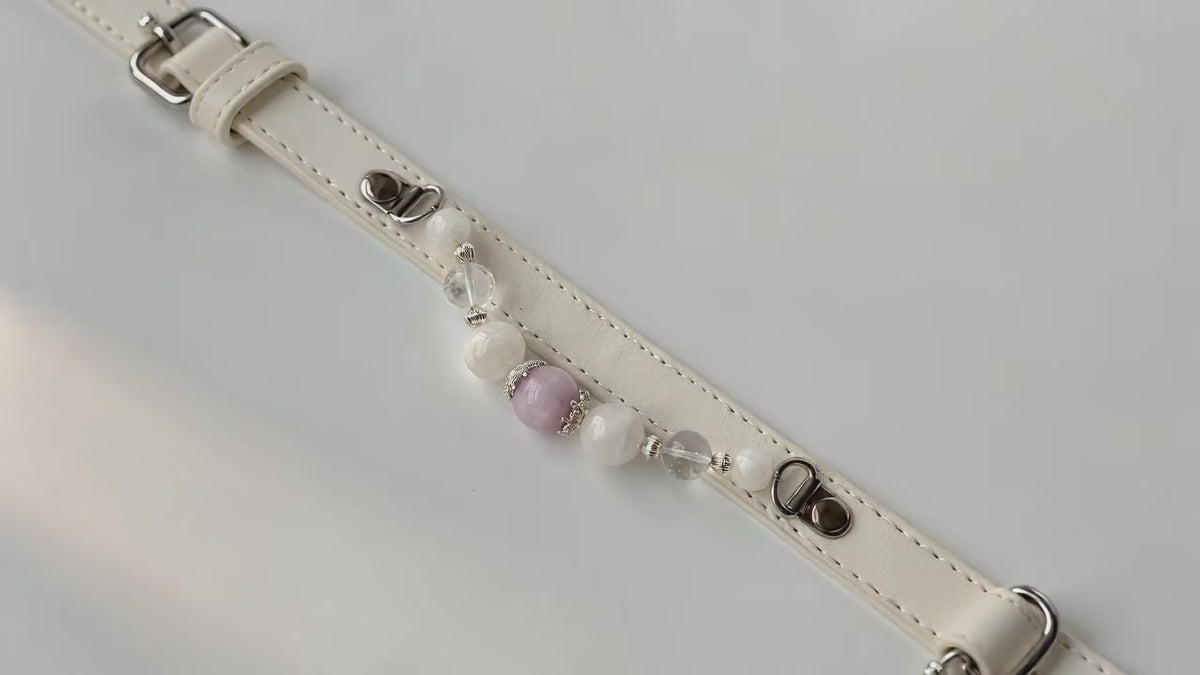 Close-up of a natural Pearl on a luxury pet collar. Warm, diffused lighting highlights the pearl's authentic ivory tones and elegant, soft luster against a delicately blurred background.